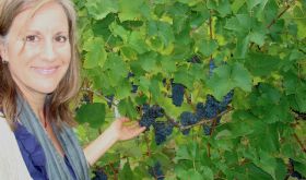 Deborah Hansen in vineyard with dark purple grapes