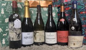 Six bottles of wine in front of Christmas presents