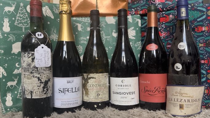 Six bottles of wine in front of Christmas presents