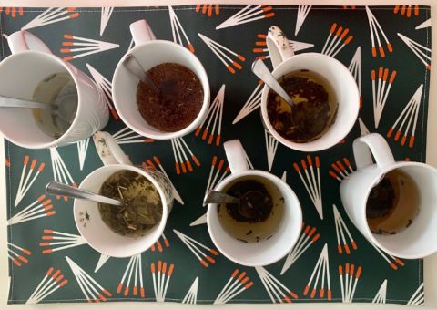 Six mugs containing wine-themed tea