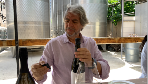 Vahe Keushguerian at table opening a bottle of wine