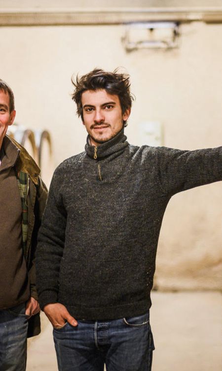 Laurent and Adrian Pillot in their wine cellar surrounded by barrels.